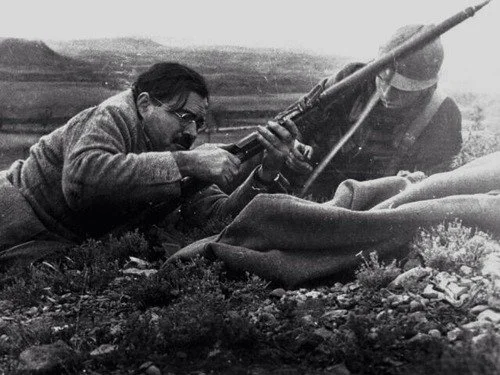 Ernest Hemingway inspects a rifle with a Republican Soldier during Spanish Civil War 1938