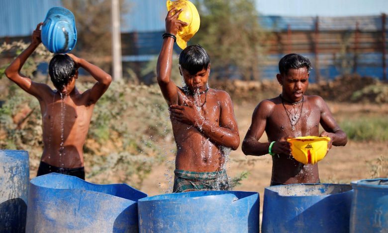 Workers use their helmets to pour water to cool themselves off near a construction site on a hot summer day on the outskirts of Ahmedabad, India, April 30, 2022. REUTERS/Amit Dave TPX IMAGES OF THE DAY