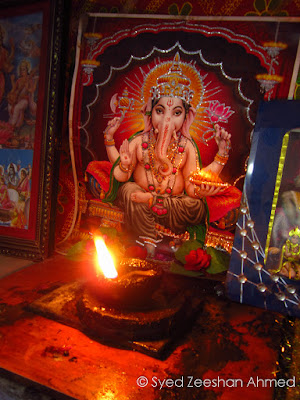 An oil-lamp (dia) right in front of a picture depicting Ganesha, a Hindu deity
