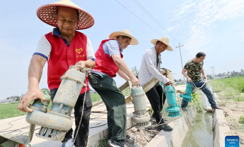 Volunteers lay pumping gears into a canal for irrigation in Xin'an Township, Deqing County, Huzhou City of east China's Zhejiang Province, Aug. 23, 2022.
