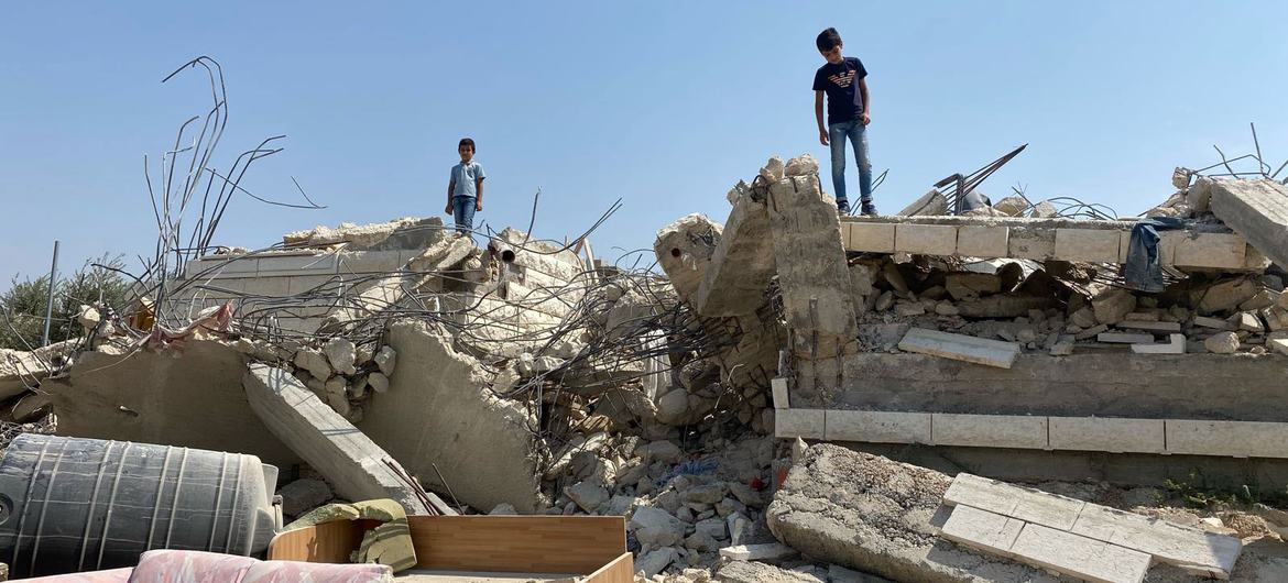 Children stand on a home demolished in Beit Sira- a Palestinian village in the central West Bank