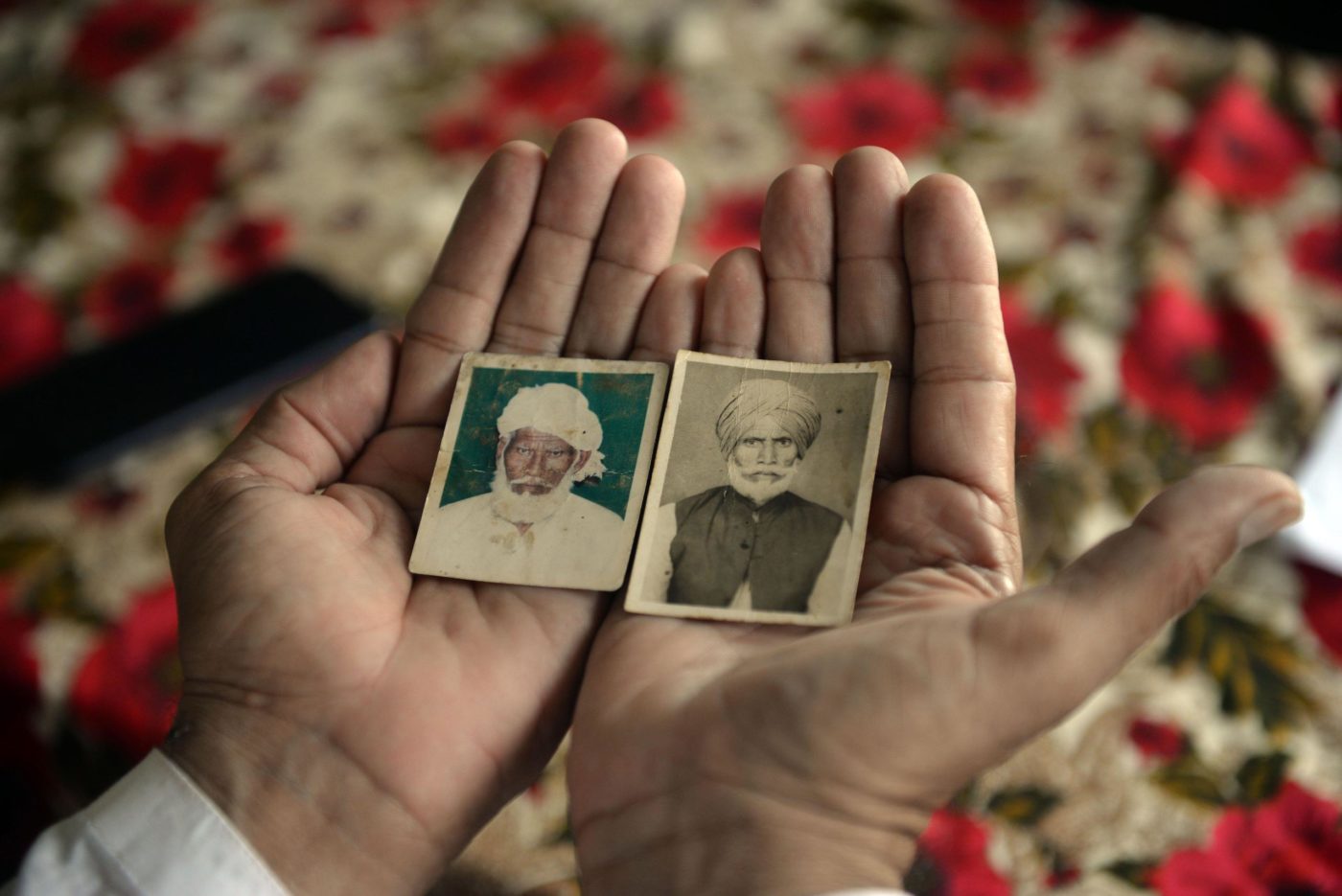05 August 2022, Pakistan, Faisalabad: Shahbaz Khan shows pictures of his uncle Inayat Khan (left), who was also separated from the family at the time of partition and died in India a few years ago, and his late father Sharif Khan. They are the brothers of