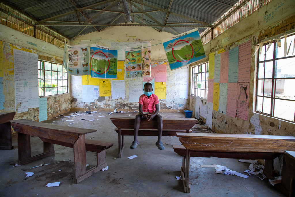 A twelve-year-old boy sits in the empty classroom of a school which was closed during the COVID-19 pandemic