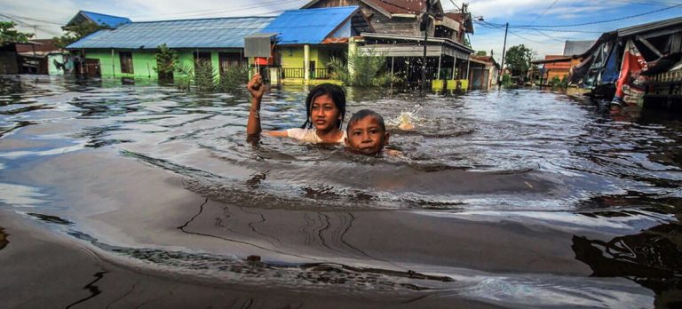 Children wade through flood water in Palangka Raya in Central Kalimantan Indonesia