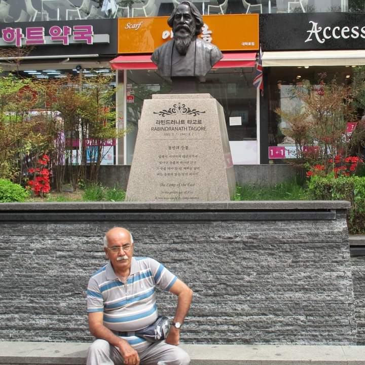 Author sitting near statue of Tagore in Seoul