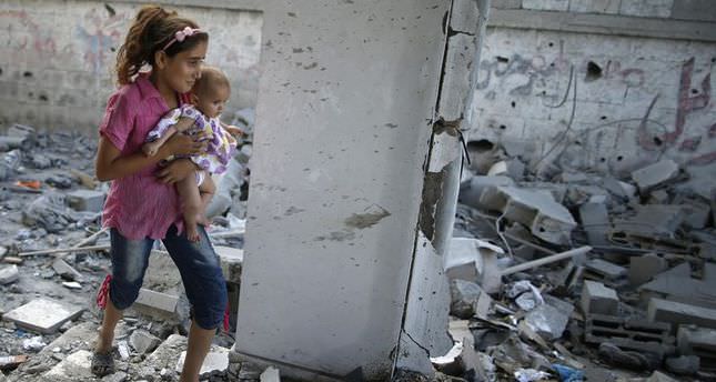 Palestinian girl holding her sister walks through debris near remains of a mosque, which witnesses said was hit by an Israeli air strike, in Beit Hanoun in the northern Gaza Strip