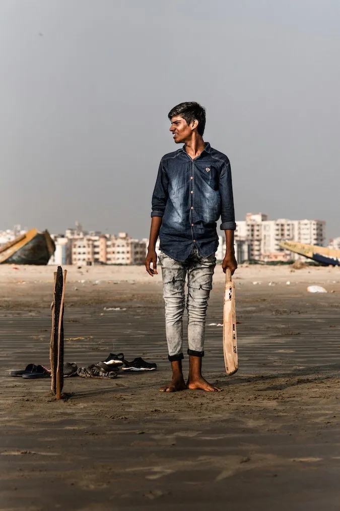 A boy plays cricket at a beach - image courtesy Unsplash