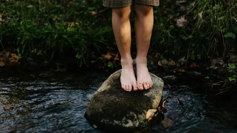 A child balances on a rock in a river - image courtesy Unsplash
